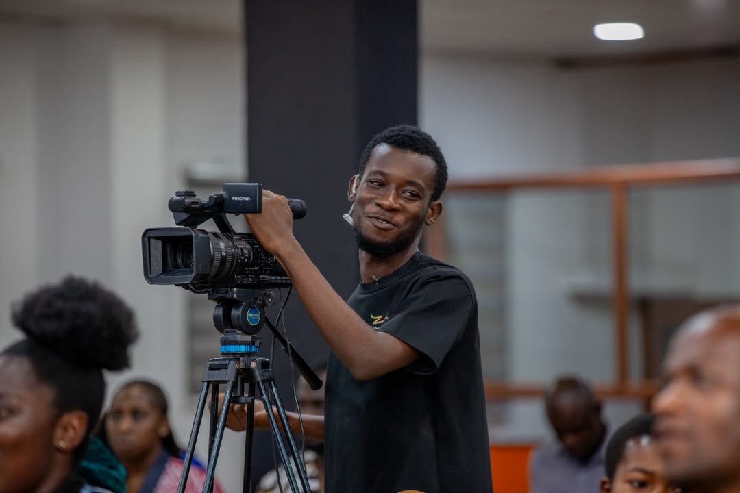 Essuman operating a video camera on a tripod